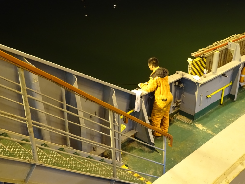 Obwohl nur wenige Meter neben ihm Container um Container verladen werden, wirft dieser Matrose seelenruhig seine Köder ins Hafenbecken und zieht enen Fisch nach dem anderen heraus