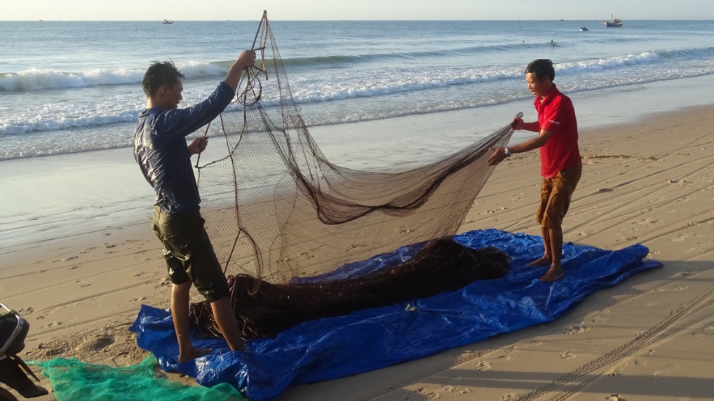 Am Strand wird das Netz auf eine ausgelegte Plache gelegt